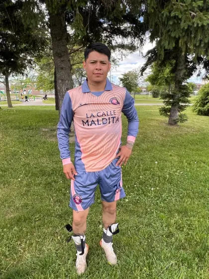 Johan Lopez, centrocampista de La Calle Maldita, con el uniforme salmón del equipo en una cancha de pasto